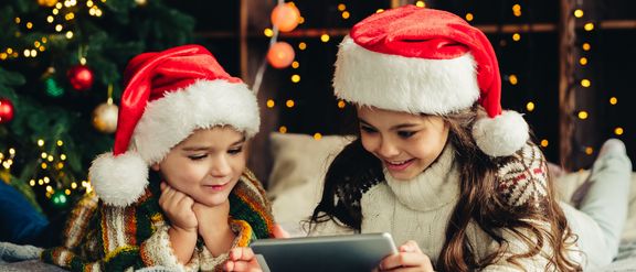 Weihnachtsfeirtage zu Hause. Glückliche Kinder mit Tablet, online spielen, Spaß haben.