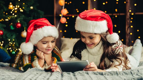 Weihnachtsfeirtage zu Hause. Glückliche Kinder mit Tablet, online spielen, Spaß haben. 