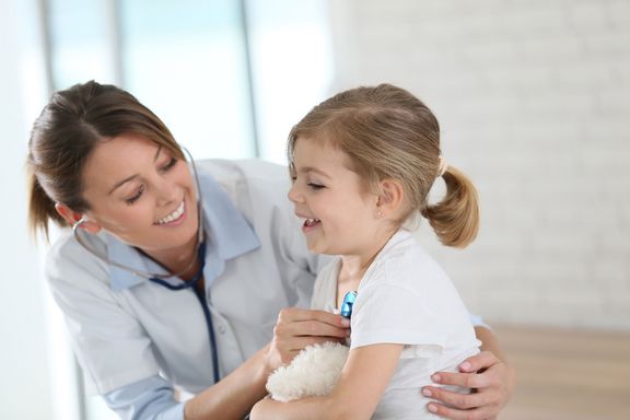 Eine Ärztin untersucht ein kleines Mädchen mit dem Stethoskop.
